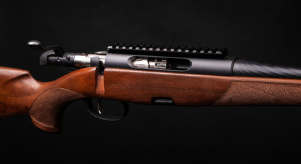 Rifle with a wooden stock on a dark back. Weapons for sports, hunting and self-defense.