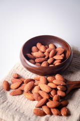 Almonds on a brown cloth in a wooden spoon