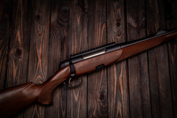 Rifle with a wooden stock on a dark back. Weapons for sports, hunting and self-defense.