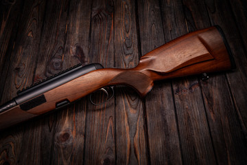 Rifle with a wooden stock on a dark back. Weapons for sports, hunting and self-defense.