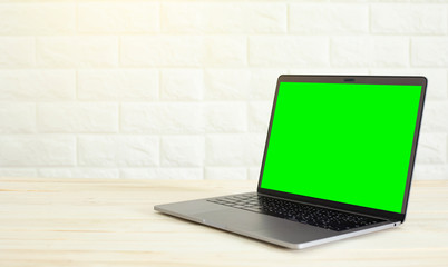 A laptop on a wooden floor and a white wall background.