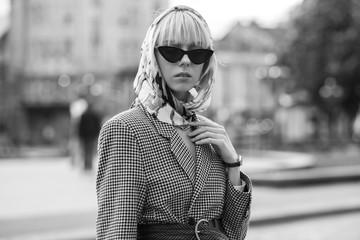Monochrome street fashion portrait of elegant woman wearing trendy headscarf, black cat eye...