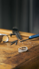 Jewelry craftsmanship. Vertical photo of a jeweller engraver tools and golden ring, diamonds on...