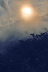 沸き立つ雲と稜線に太陽が沈む直前
