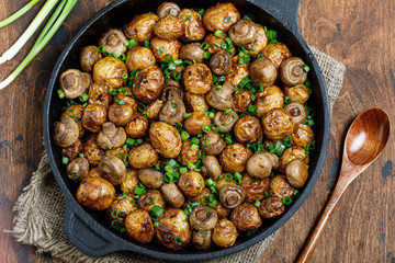 Delicious baked potatoes in cast-iron pan with champignons and green onion. Dish for dinner