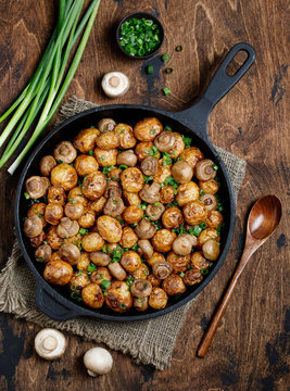Delicious baked potatoes in cast-iron pan with champignons and green onion. Dish for dinner