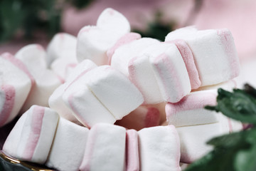 Fototapeta na wymiar Airy white and pink marshmallows on a plate decorated. Macro. Soft focus..