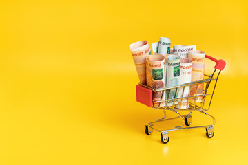 Russian ruble banknotes in shopping cart on yellow background. Economic concept of food basket...