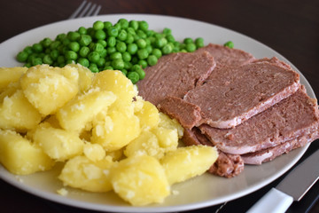 Corned beef with potato and green peas.  Selective focus.