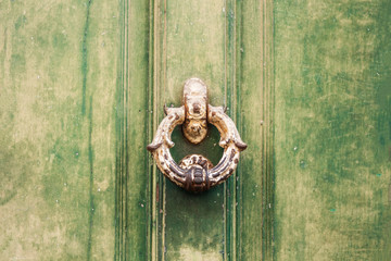 Antique metal handle on an entrance wooden door in an old building, retro concept background.