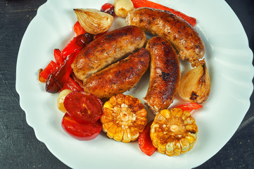fried homemade sausages with vegetables on a plate .cooking at home . the view from the top