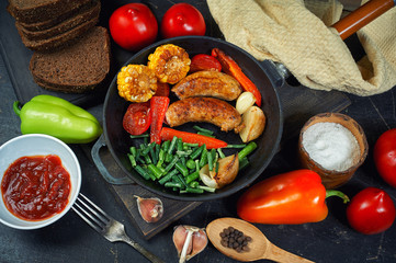 fried homemade sausages with vegetables in a pan .cooking at home