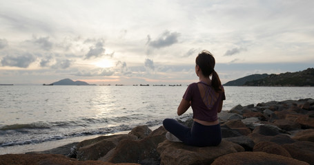 Woman do yoga and sit beside the sea