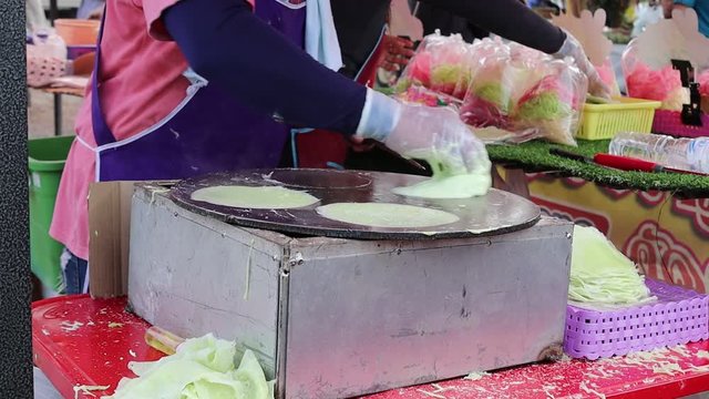 Man cooking Thai cotton candy burrito pancake (Roti Saimai) for sell at flea market