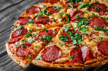 Pepperoni Pizza with Mozzarella cheese, salami, Tomato sauce, pepper, Spices and Fresh basil. Italian pizza on wooden table background