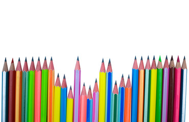 Scattered line of different colored wood pencil crayons placed on a white paper background