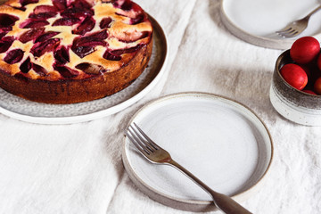 Homemade Ricotta Plum Cake on beige linen tablecloth. Cottage cheese casserole with vanilla, semolina and plums. Selective focus
