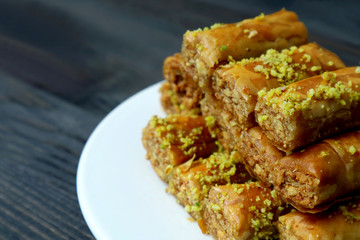 Closeup Pile of Mouthwatering Baklava Pastries with Pistachio Nuts on a White Plate
