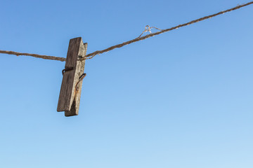 Wooden clothespin on a rope. Subject against the sky. Space for notes. Dry clothes. Decorative clip in the interior. Household work. Attach anything. Heavenly background. Empty clothesline.