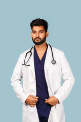 Handsome modern Indian / Asian doctor with stethoscope, in uniform on blue background