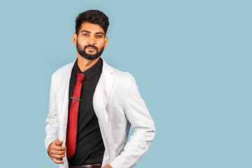 Handsome modern indian / asian doctor with stethoscope, tie and white coat on blue background