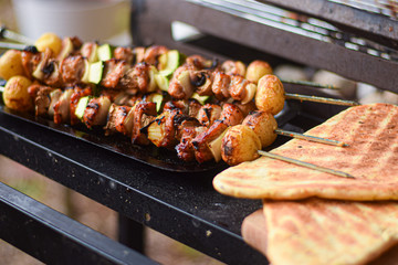 Freshly grilled meat and vegetable skewers with flat bread on outdoor barbecue