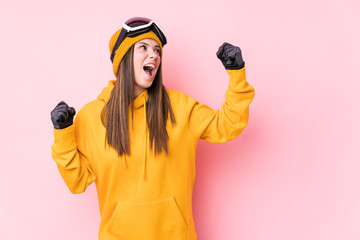 Young caucasian skier woman isolated raising fist after a victory, winner concept.