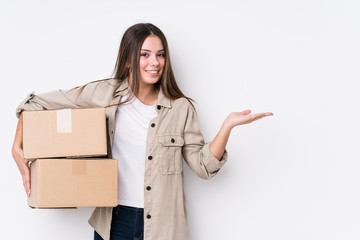 Young caucasian woman moving to a new home showing a copy space on a palm and holding another hand on waist.