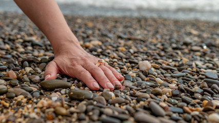 Ring at sea, on hand put on a sea ring of water, on a rocky beach idea for a photo