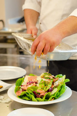 cook prepares salad by hand.