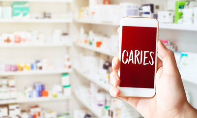 Hand in medical glove holding smartphone on white background. Blank screen with CARIES text.