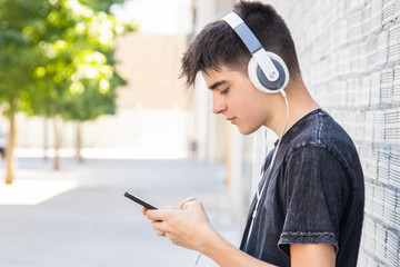 male teenager with headphones and phone on the street