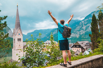 happy man tourist standing with rising up hands looking at hallstatt city from above