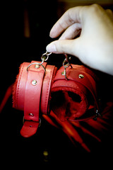 Womans hand holding handcuffs and whip for sex games