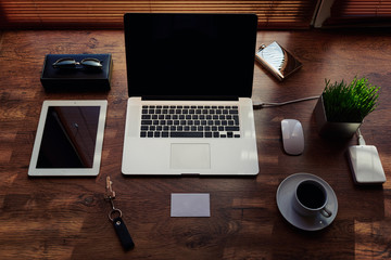 Mock up of freelance desktop with accessories and distance work tools, blank screen laptop computer and digital tablet, mouse, sunglasses, cup of coffee, touch pad and hard drive, business workspace