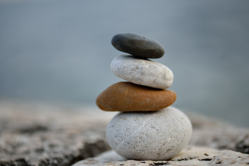 Fototapeta na wymiar Stone cairn on striped grey white background, five stones tower, simple poise stones, simplicity harmony and balance, rock zen sculptures
