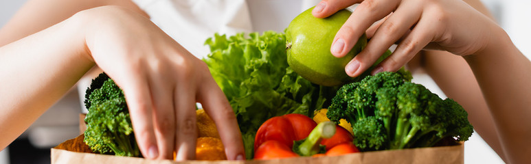 horizontal crop of woman touching groceries in paper bag