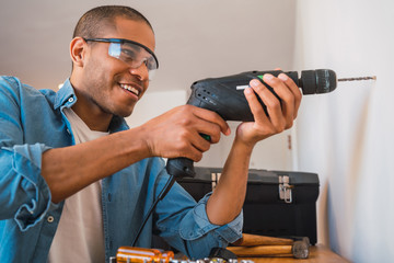 Young man with a electric drill and making hole in wall.