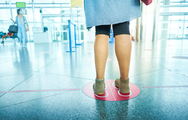 Woman waiting at the airport maintaining social distancing. Social distance to avoid Covid 19.