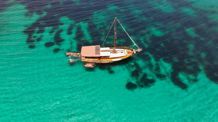 Fototapeta na wymiar Aerial drone top down photo of piratesboat, yacht with wooden deck anchored in open ocean sea