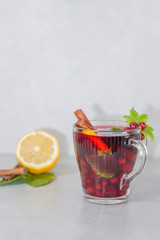 Red drink with fruits, lemon and cinnamon on a light background