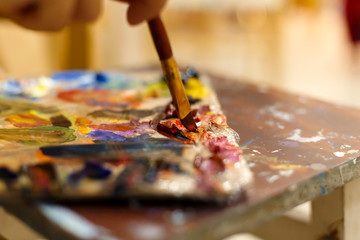 Obraz premium Close-up of an easel with paints, the artist paints a brush. Painting a picture.