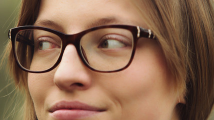Face expression of a young woman with glasses over her green eyes. Close up portrait. High quality...