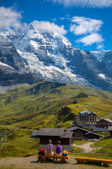Fototapeta na wymiar Hikers resting above the village of Kleine Scheidegg and The Eiger, a mountain of the Bernese Alps, overlooking Grindelwald and Lauterbrunnen in the Bernese Oberland of Switzerland