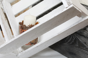 Obraz premium A candle in a glass candlestick. The candlestick is filled with dried cones, spices and dried fruits. Stands in a wooden box.