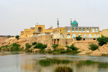 Fototapeta na wymiar In Iran, the city of Shushtar is a green oasis surrounded by desert. A mosque is situated along the river. 