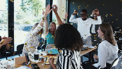 Coronavirus lockdown ending. Happy multiethnic business team taking masks off, celebrate victory with confetti at office