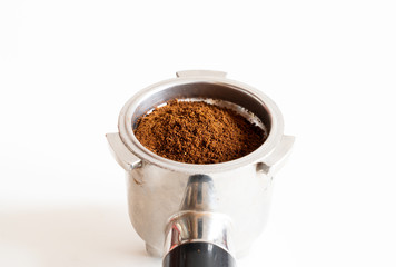 Portafilter filled with ground coffee on white background