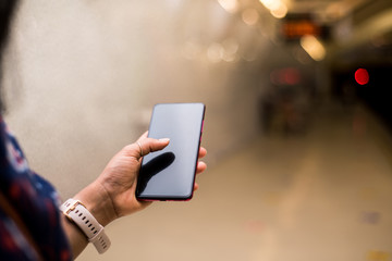 Woman finger touching the black screen of smart phone on the train station. Concept of technology on the transport.
