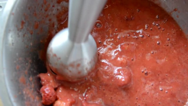 Berries are crushed with a blender. Strawberries are ripe in the preparation of the drink. Ingredients for smoothies.